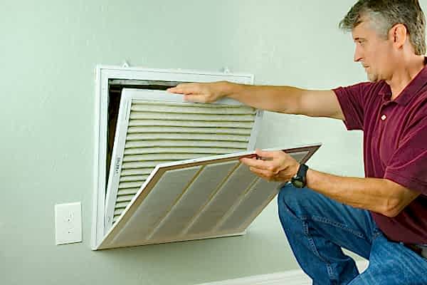 Man replacing air filter from air vent