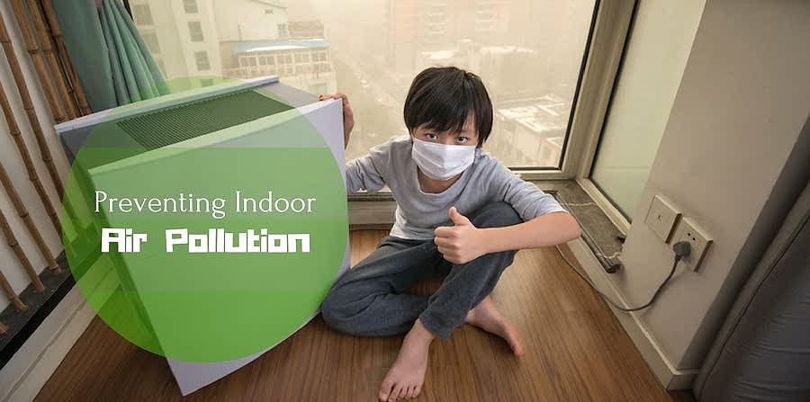 Boy giving thumbs up while sitting next to an air purifier and wearing a face mask. Smoggy city visible in window behind him. "Fighting Indoor Air Pollution."