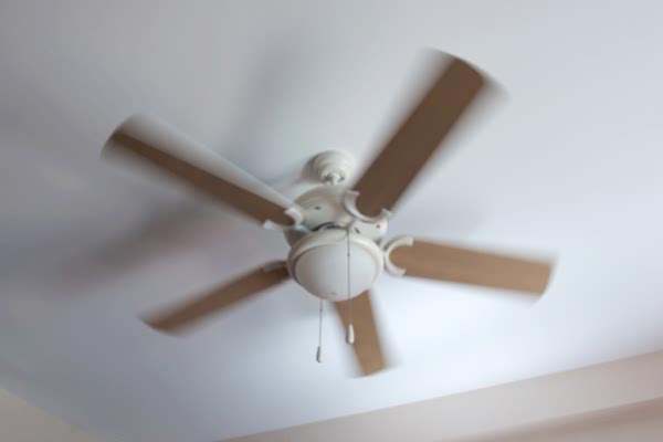Ceiling fan with wooden blades in a white room