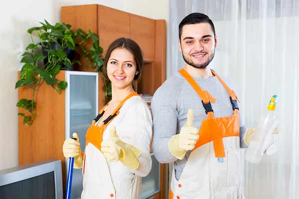 Two roommates decked out and ready to clean, giving thumbs up