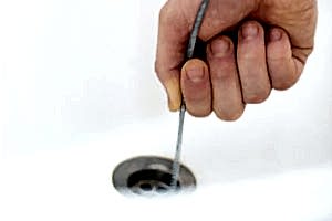threading a plumber's snake into a drain