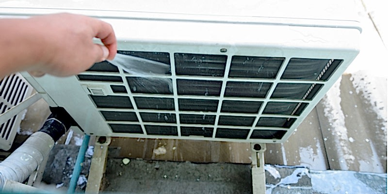 Cleaning out the front of an air conditioner's condenser unit