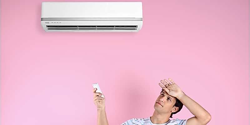 Sweating, uncomfortable-looking man tries to turn on his indoor air conditioner