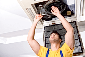 Technician prepares an HVAC system for spring with an inspection