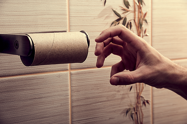 Hand reaching for used-up toilet paper roll