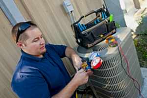 A repairman examines a air conditioning unit.