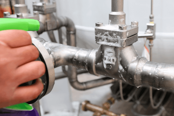 A spray bottle spraying soapy water onto a gas line.