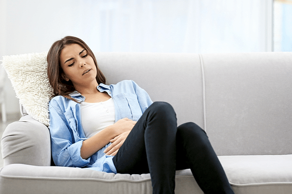 A woman sits on the couch, nauseous from a natural gas leak in her home.