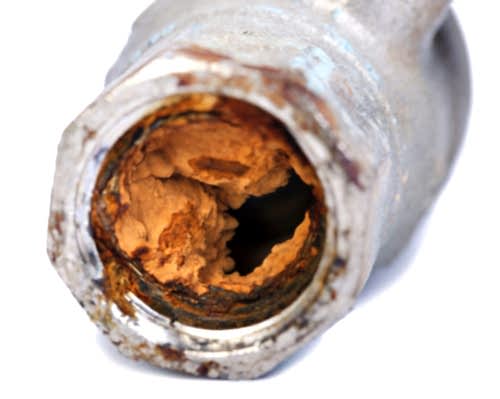 A home pipe filled with orange corrosion.