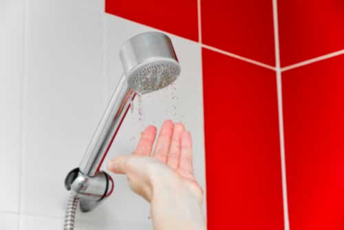A homeowner puts their hand beneath a light shower trickle.
