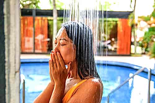 A woman showers off next to her home's inground pool.