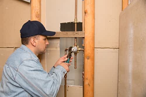 A plumber connects new shower pipes during a bathroom remodel.