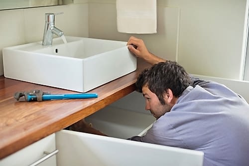 A plumber connects a new bathroom sink.